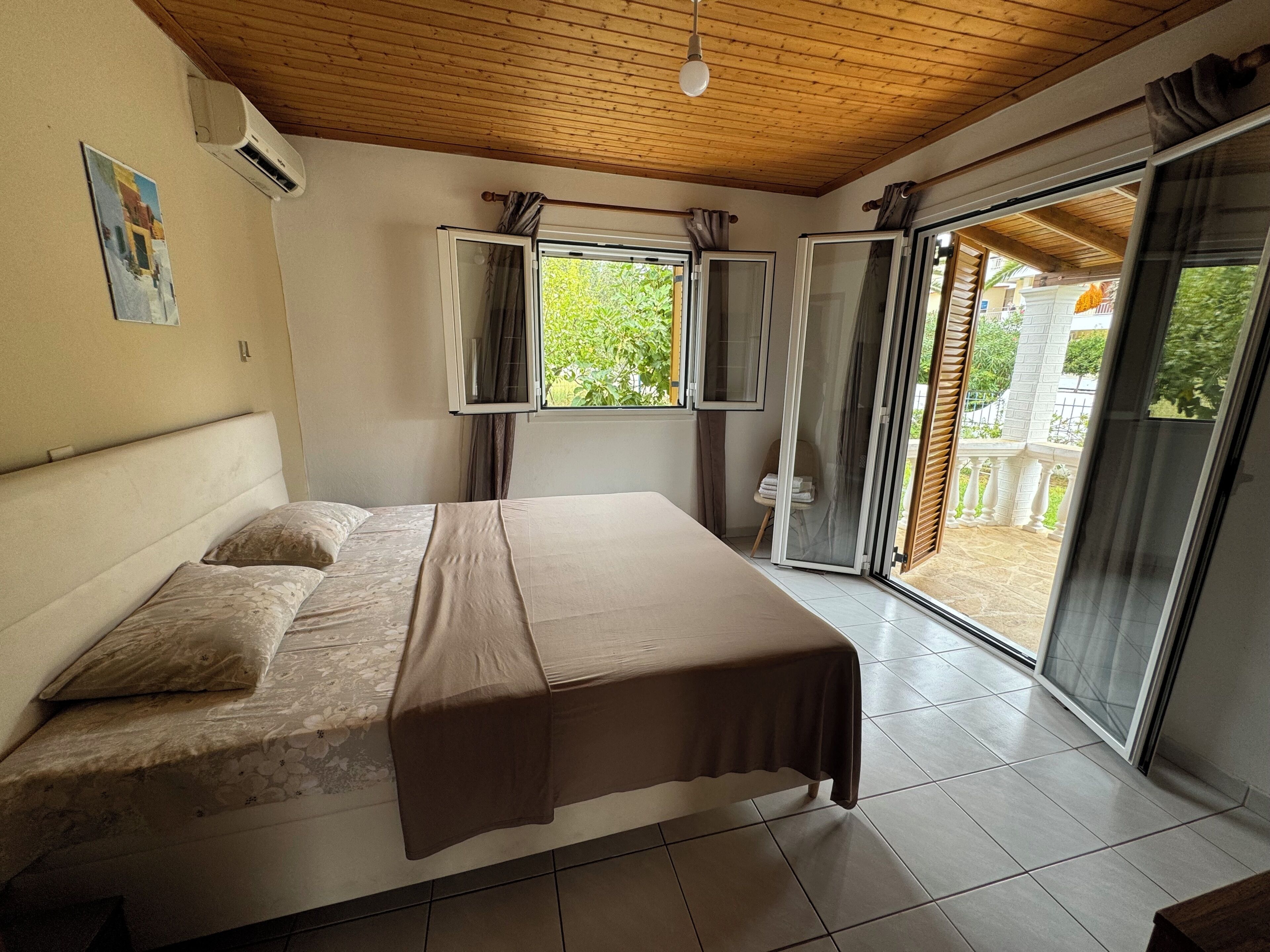 Una camera da letto con un letto, una finestra e una porta scorrevole in vetro che dà su una zona esterna.