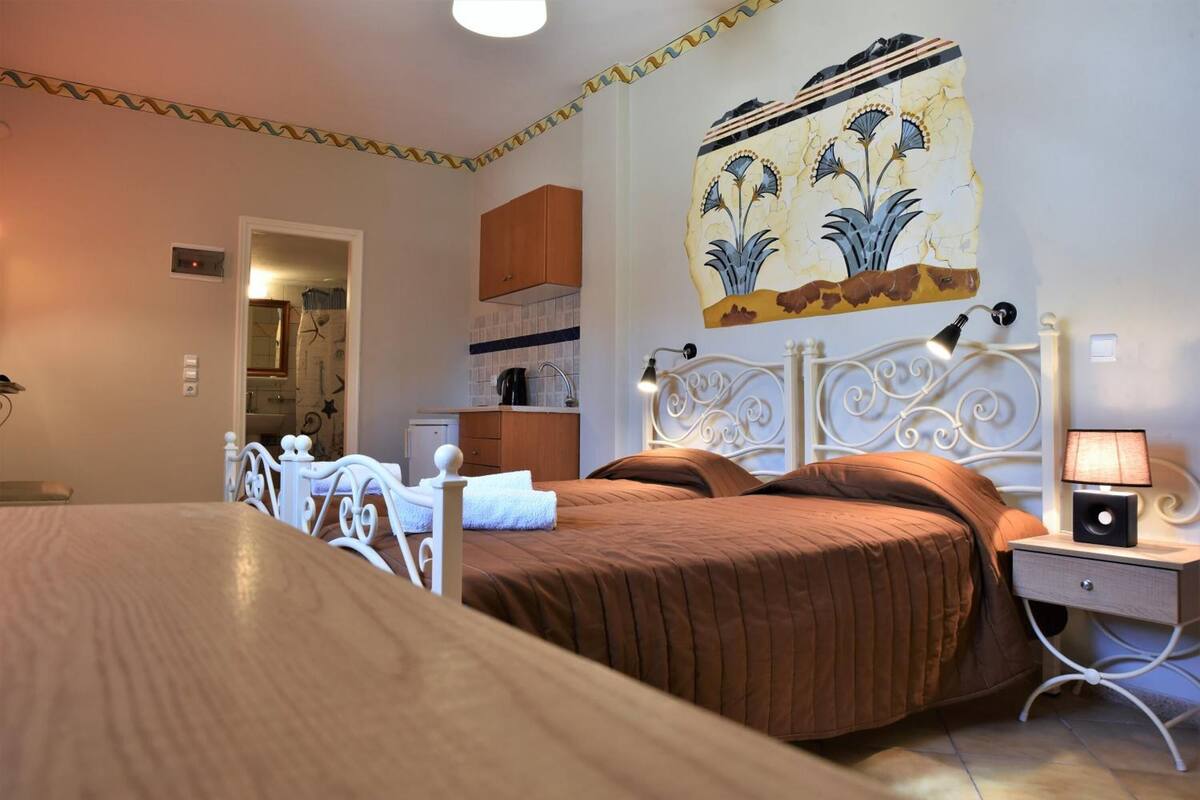 Un dormitorio con cama, mesita de noche, lámpara y una pared decorada con azulejos.