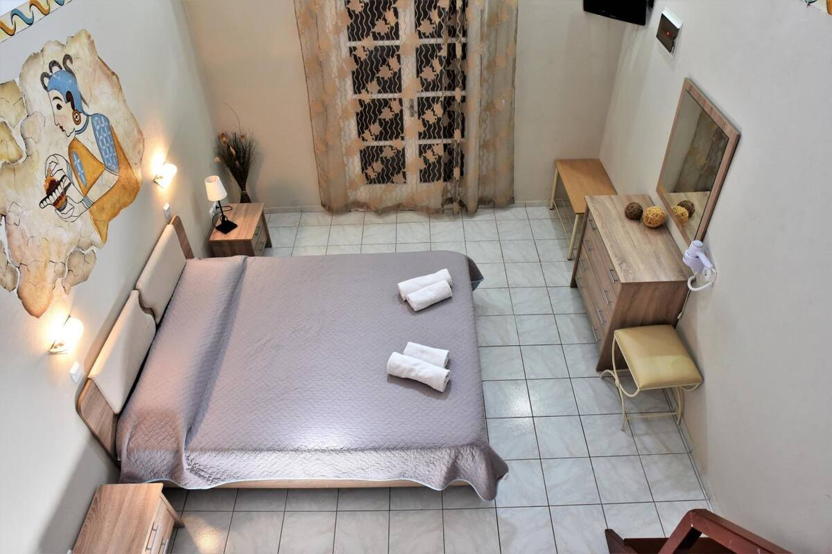 Un dormitorio ordenado con cama, mesita de noche y espejo.