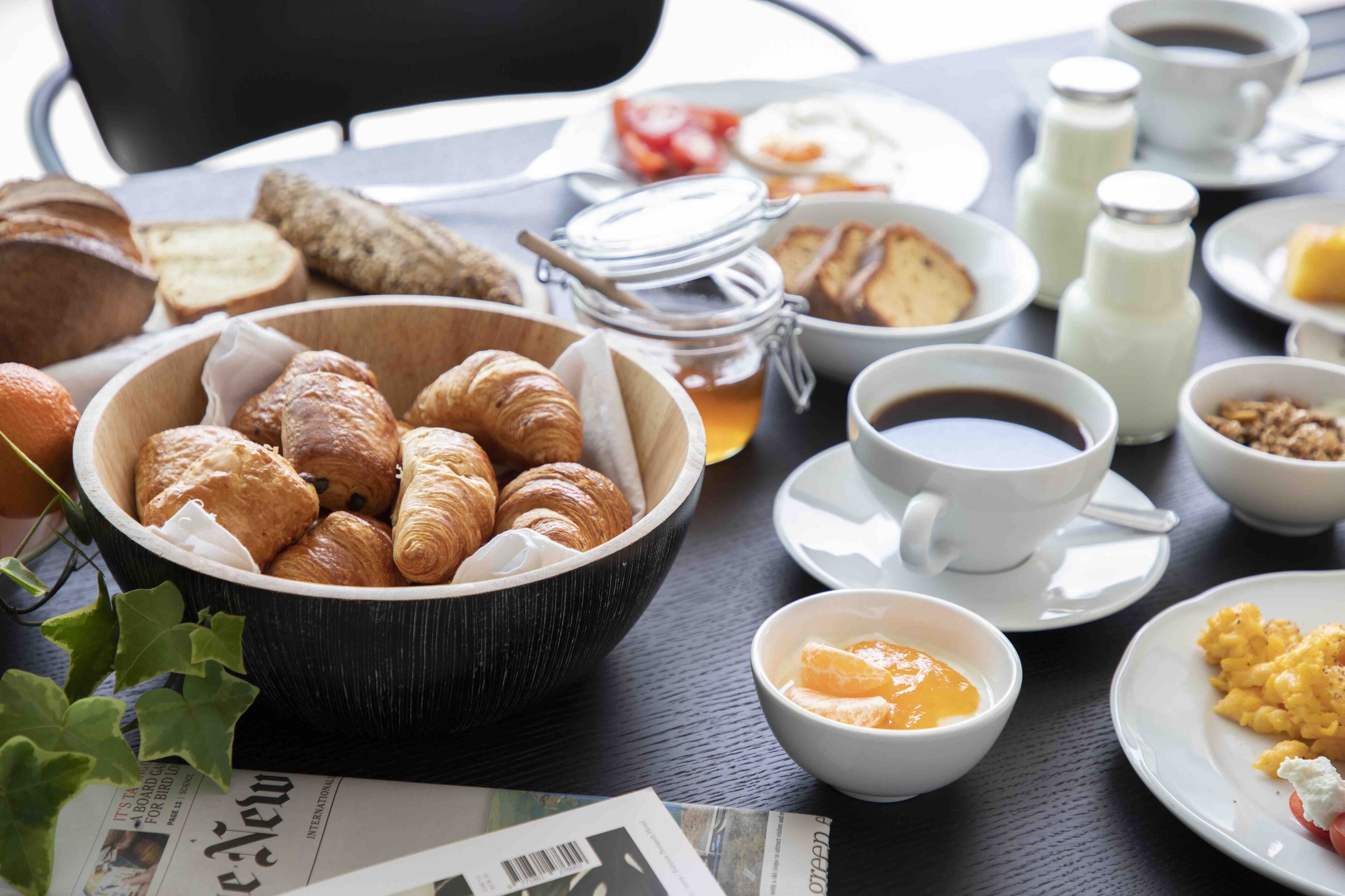 A breakfast table with croissants, coffee, orange juice, and various breakfast items.