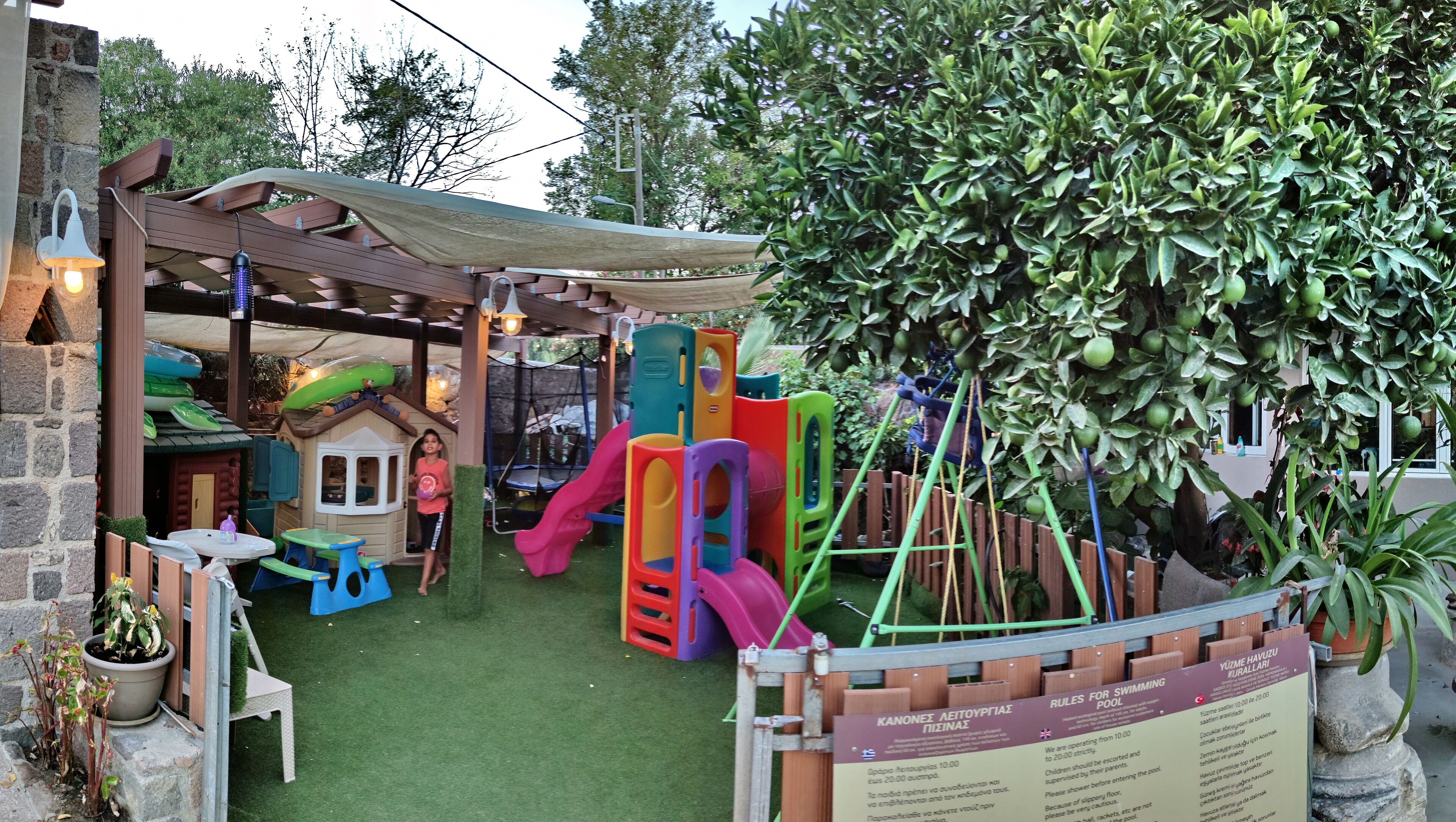 Zona de juegos infantiles con un tobogán, estructuras para escalar y una casita.
