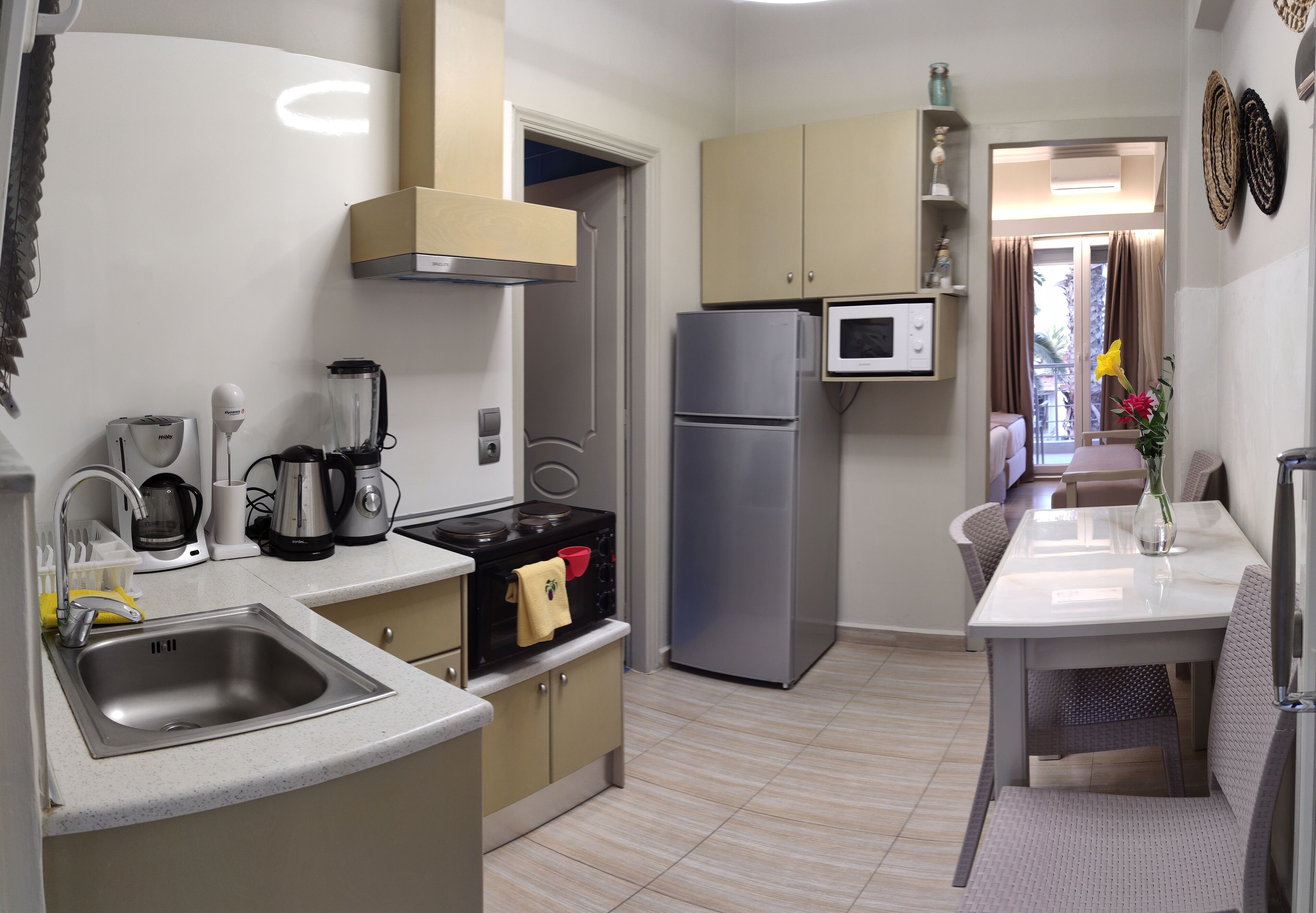 A compact kitchen with a sink, stove, microwave, and refrigerator. There is a dining area with a table and chairs.