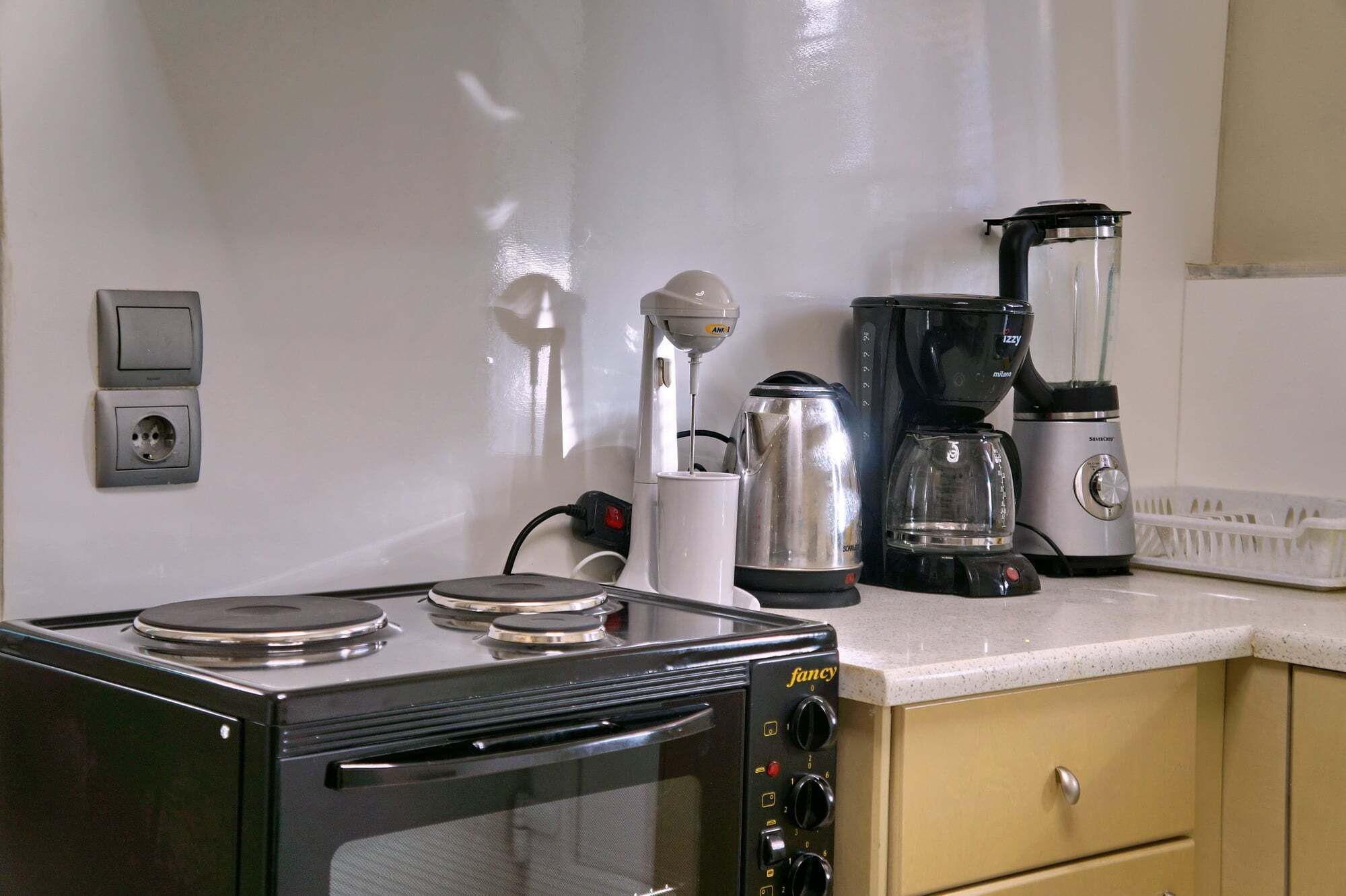 Una kitchenette equipada con estufa, cafetera, licuadora y hervidor.