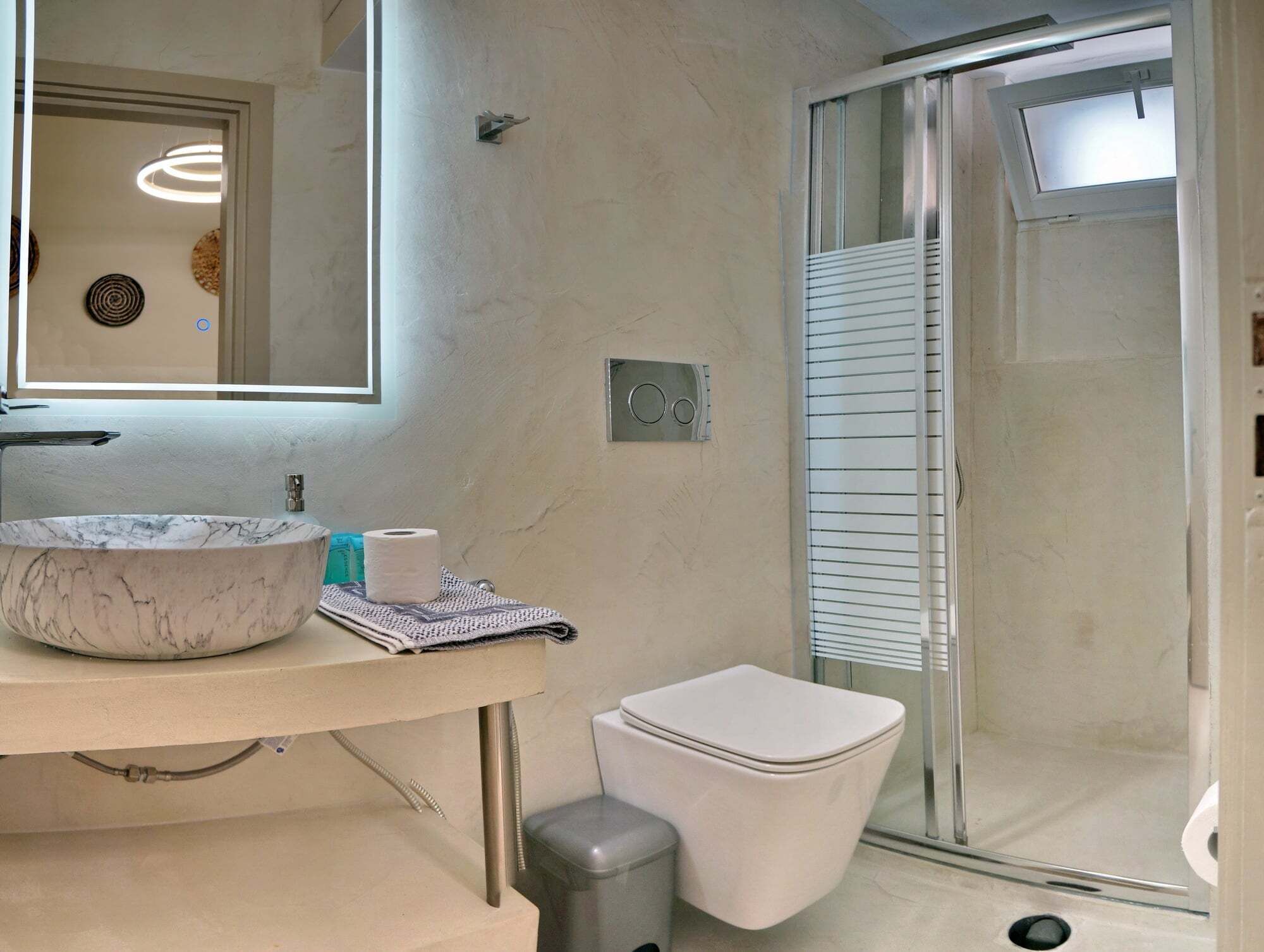 A bathroom with a marble sink, toilet, and a glass shower enclosure.
