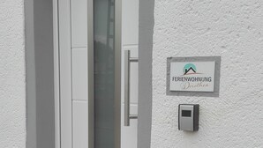 A white door with a frosted glass panel, a small mailbox, and a sign that reads "FERIENWOHNUNG Dorothea" on a textured wall. - Ferienwohnungen Paul und Dorothea (Döllstädt)