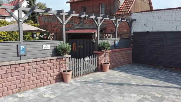 A gated parking area with a brick wall, a pergola, and potted plants. - Ferienwohnungen Paul und Dorothea (Döllstädt)