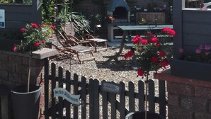 A garden with a wooden pergola, a barbecue area, and a wooden fence with a sign. - Ferienwohnungen Paul und Dorothea (Döllstädt)