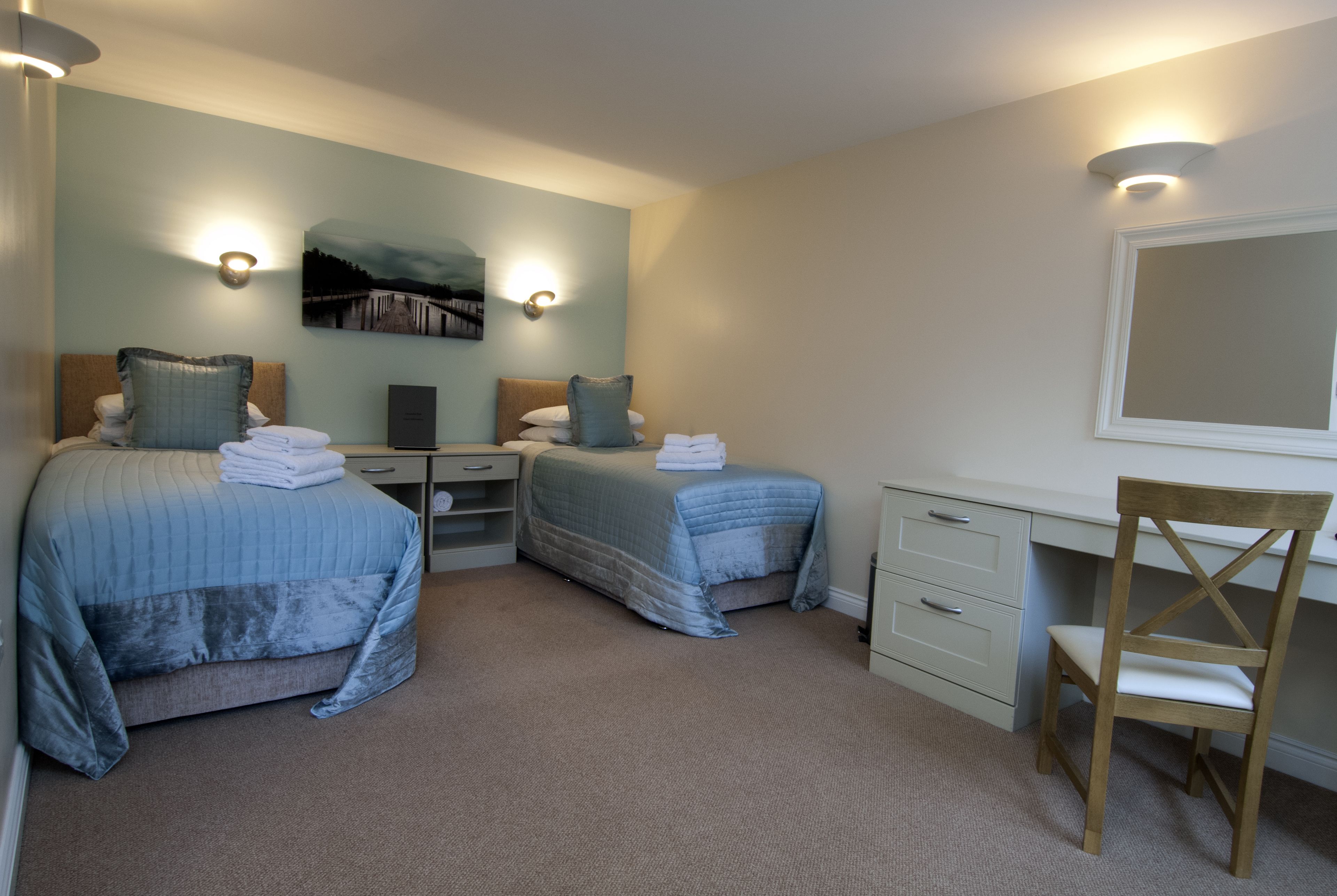 A bedroom with two beds, a desk, and a chair.