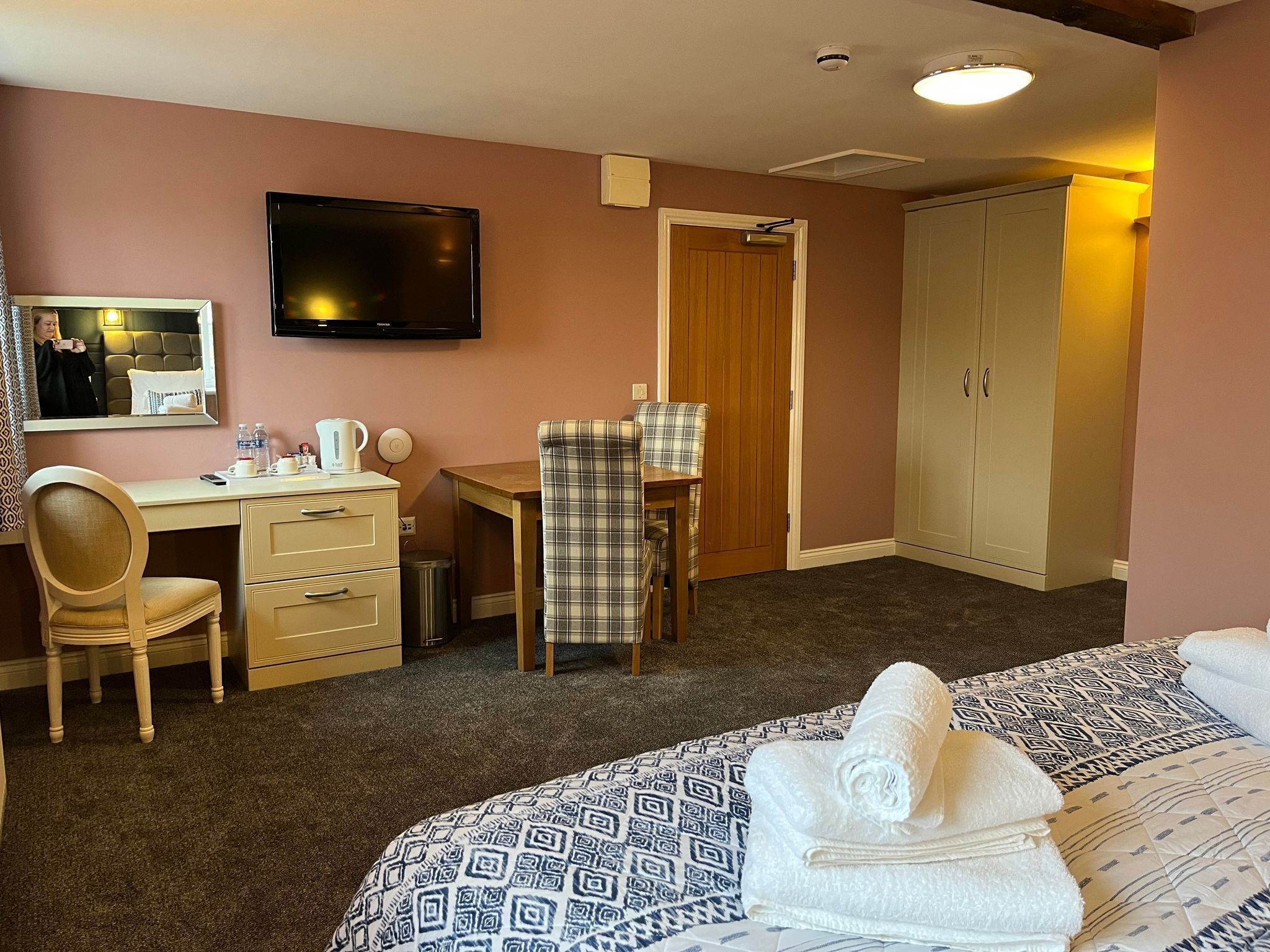 Una habitación de hotel con cama, escritorio, silla, televisor y armario.