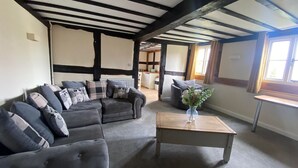 A cozy living room with a dark-colored sofa set, a wooden coffee table, and a view of the adjacent kitchen through an open doorway. - Alexander Park Resort (Ledbury)