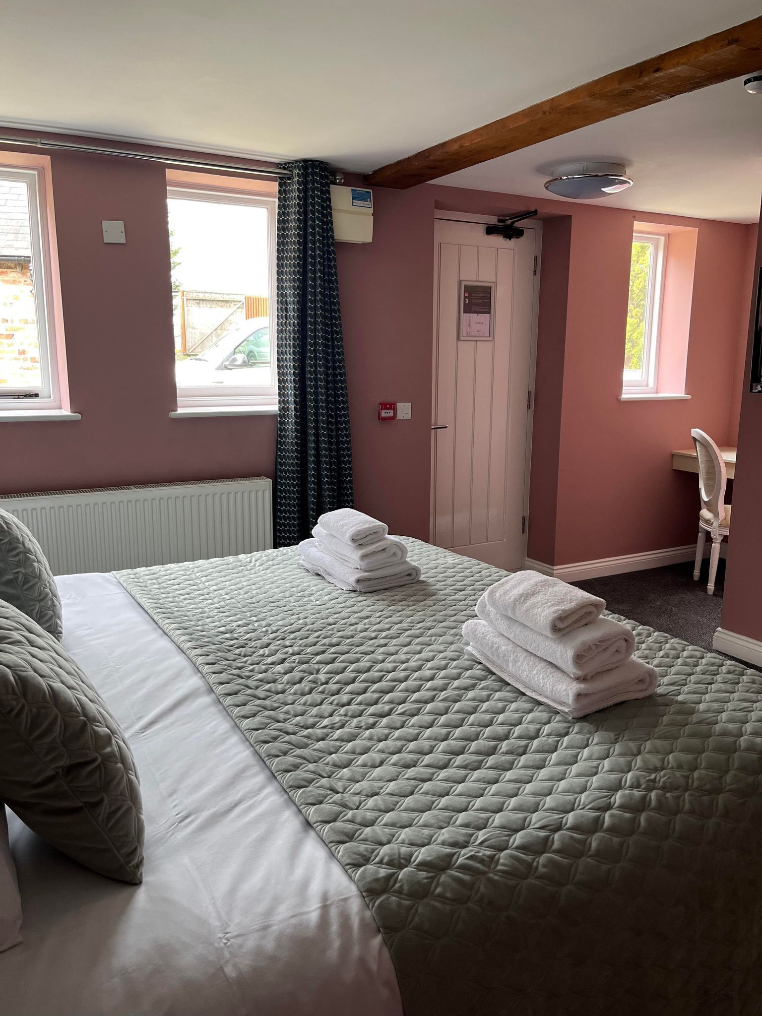 A hotel room with a bed, a desk, and a window.