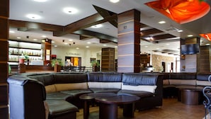 Un área de estar moderna con sofás de cuero, un bar y un restaurante al fondo.