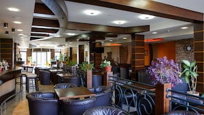 Un restaurante con asientos de cuero, una zona de bar y plantas en macetas.
