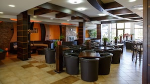 Un espacio interior amplio con varias opciones de asiento, incluyendo sofás y sillones, y una zona central con mostrador.