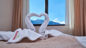 Una habitación de hotel con una cama, una ventana con cortinas y una toalla doblada en forma de corazón.