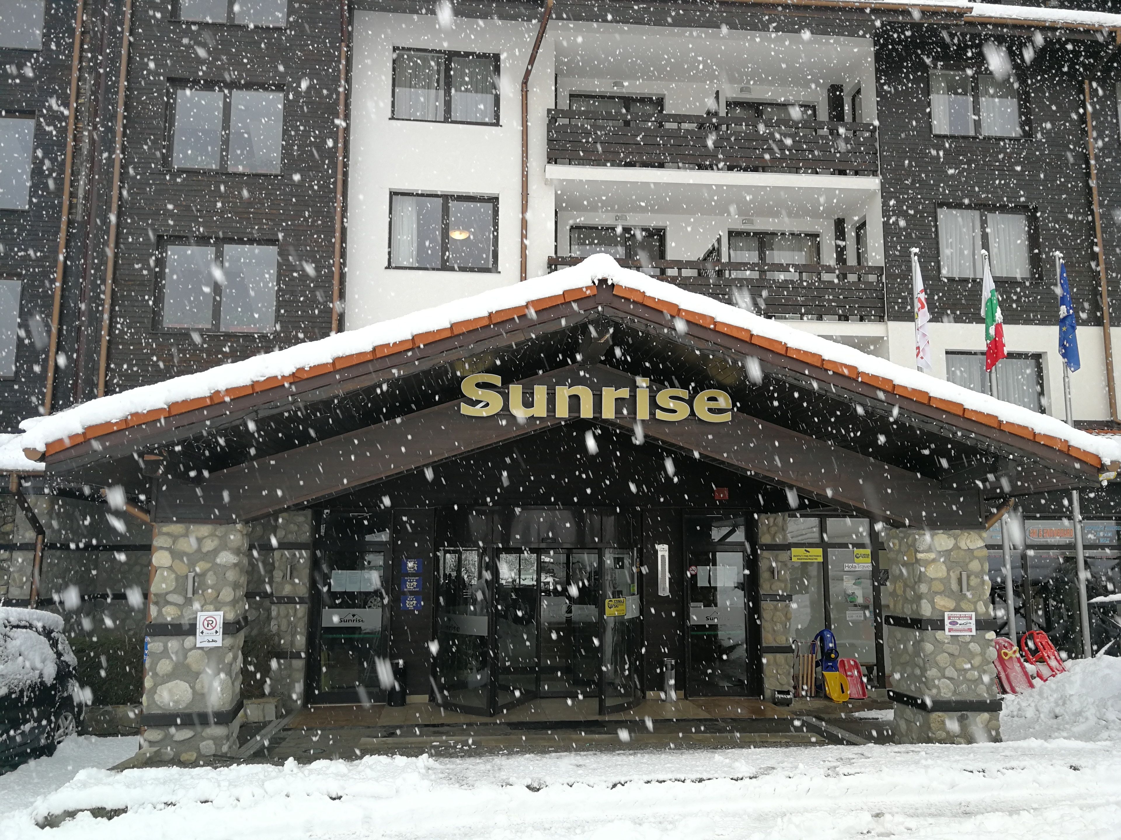 Un hôtel appelé Sunrise, doté d’une façade en pierre et d’un toit en pente recouvert de neige.