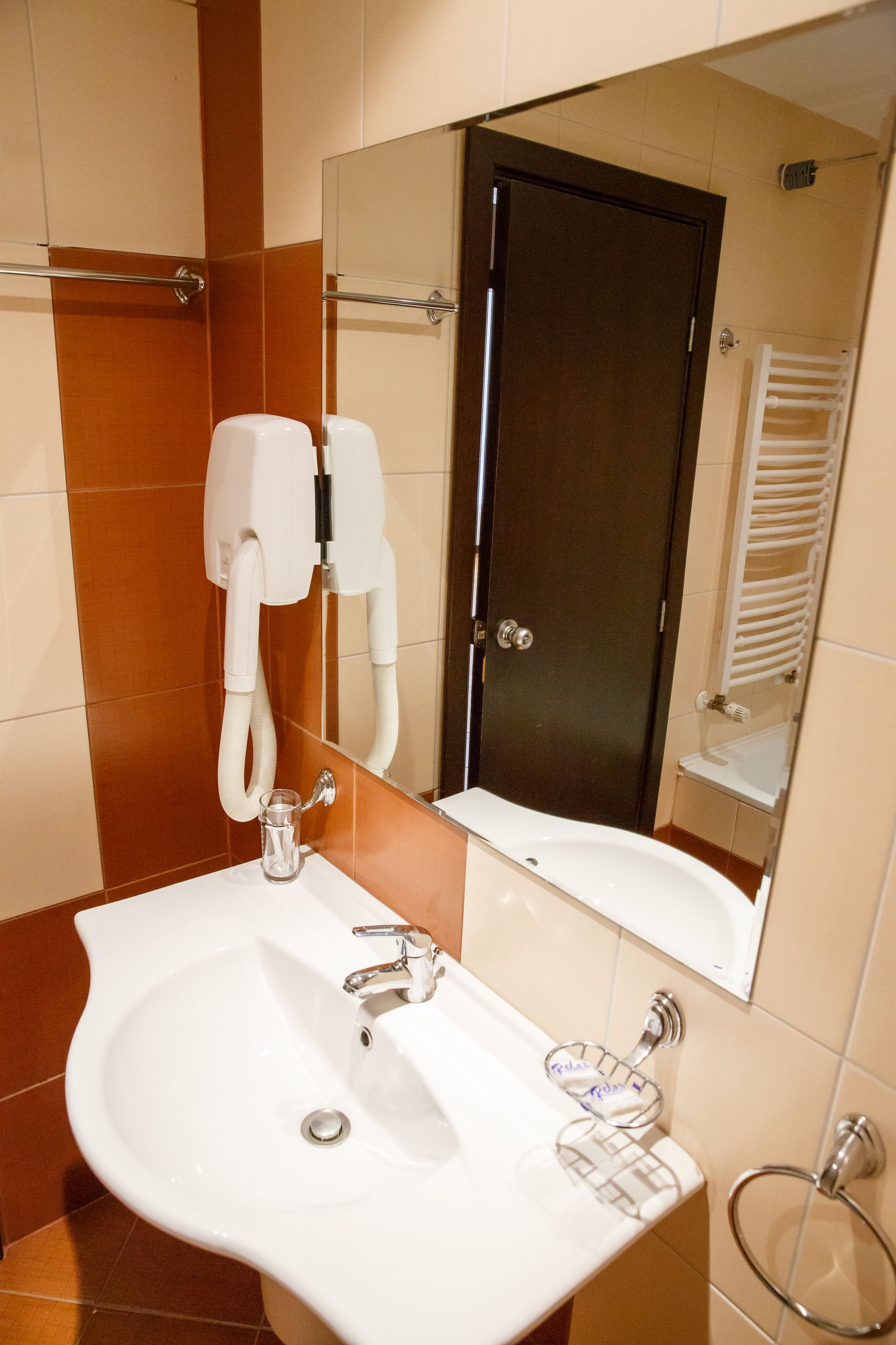 A bathroom with a white sink, a mirror, a towel rack, and a door.