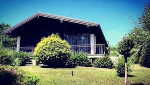 Une maison moderne avec un toit en pente, de grandes fenêtres et une pelouse bien entretenue.