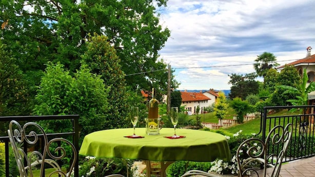 Un espace extérieur aménagé pour prendre les repas, avec une table ronde, deux chaises et une bouteille de vin.
