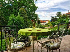 Et udendørs spiseområde med et rundt bord, to stole og en flaske vin.