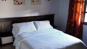 A bedroom with a bed, two wall-mounted lamps, and three wall art pieces.