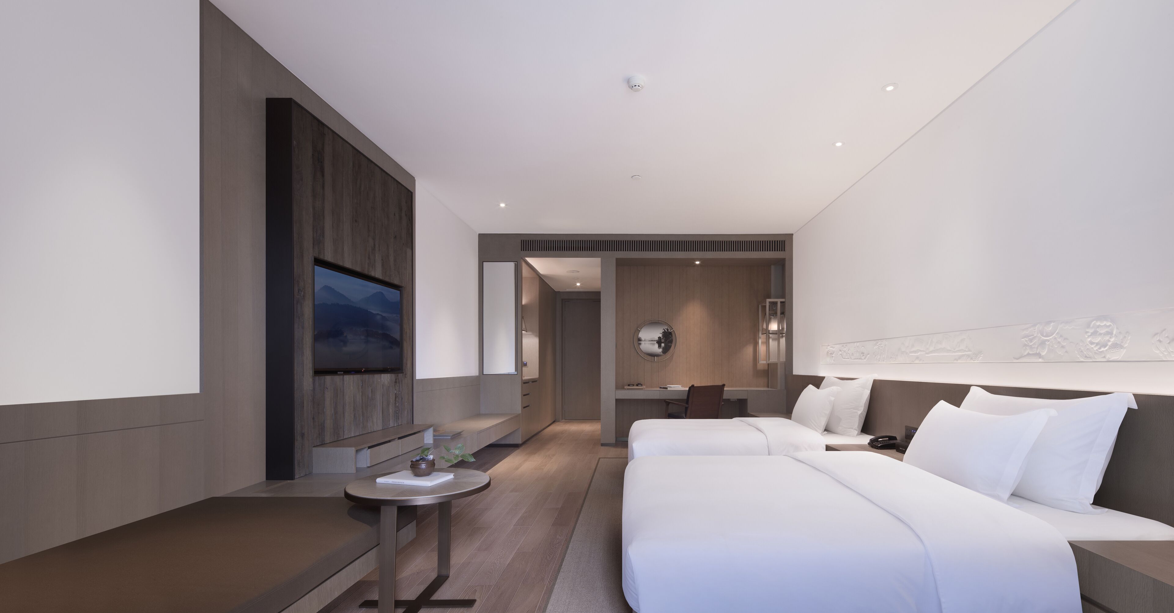 A modern hotel room with a large bed, a desk, and a seating area.