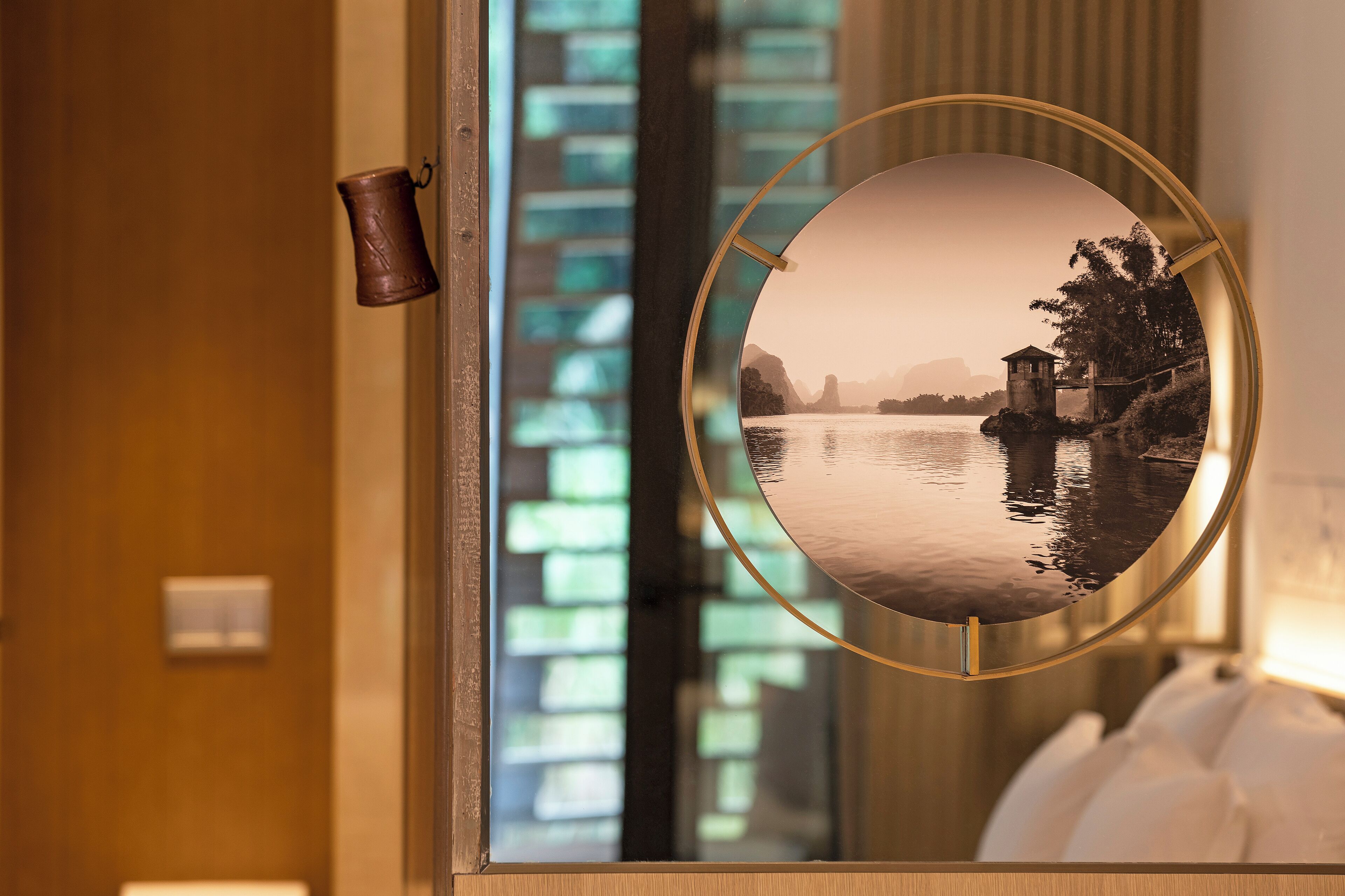 A mirror reflecting a serene lakeside view with a small building and trees.