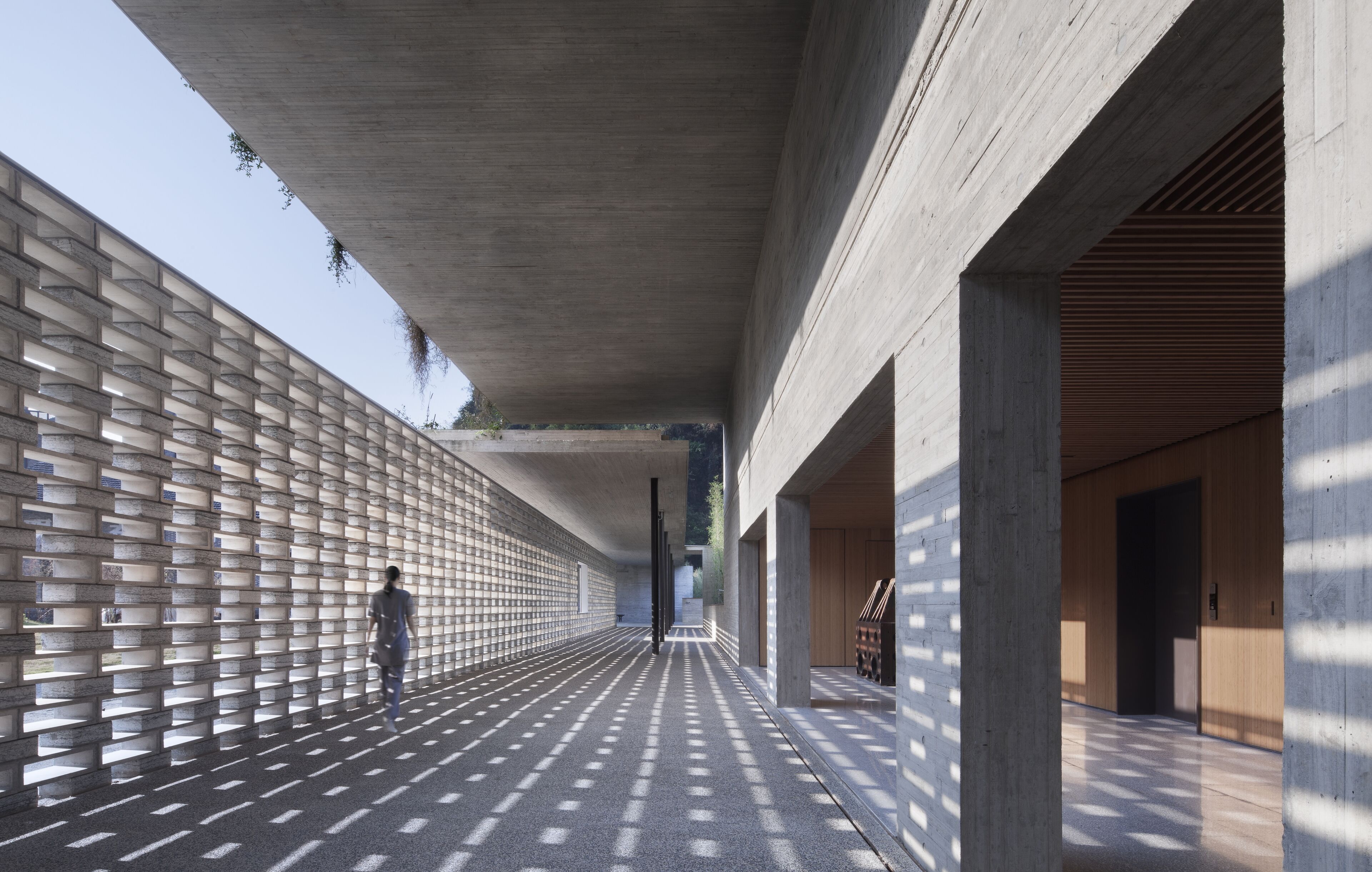 Un pasillo con pared de diseño, techo de hormigón y detalles de madera.