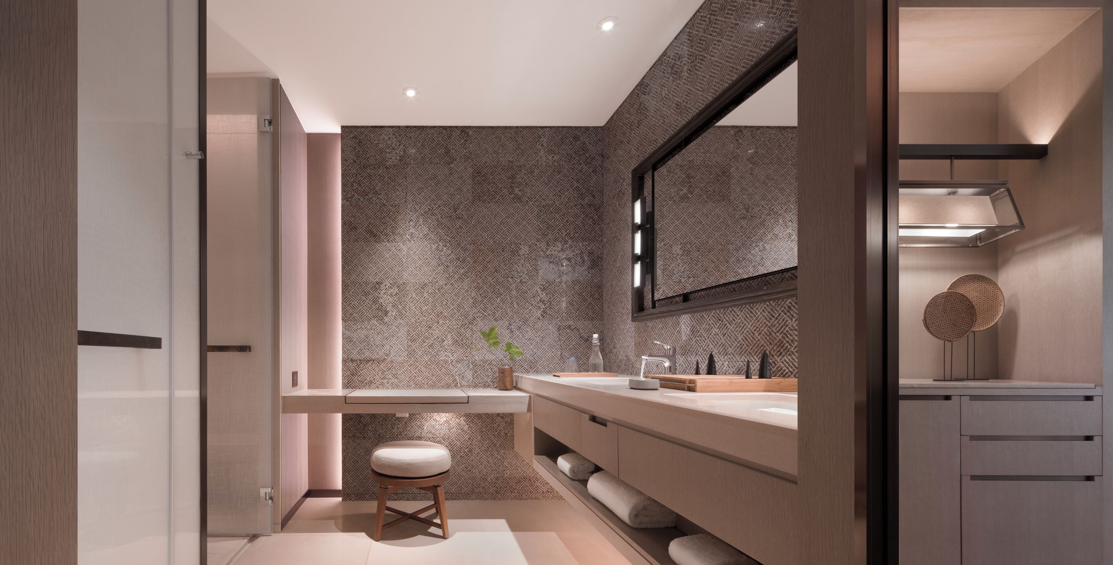 A modern bathroom with a large mirror, a sink, and a stool.