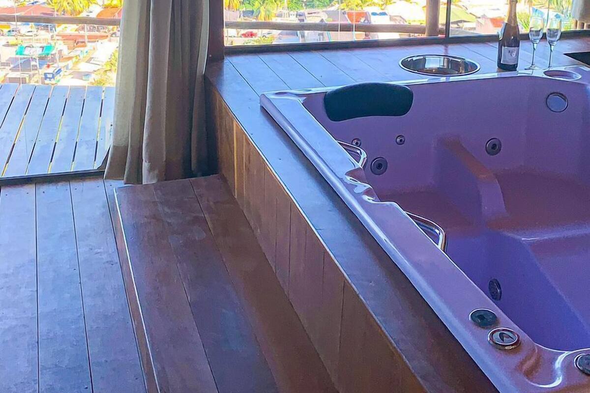 A wooden deck with a hot tub and a view of the ocean.