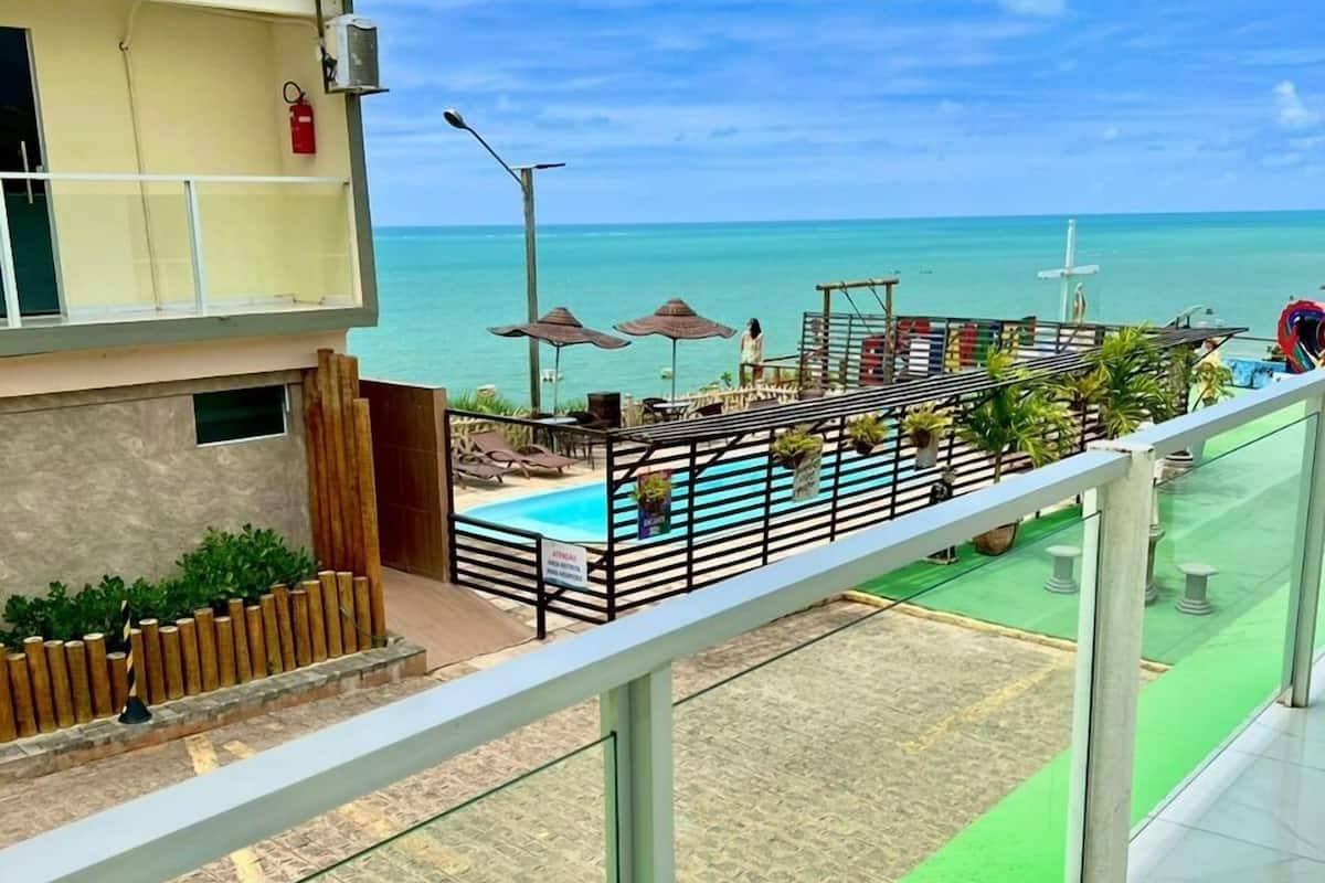 A balcony with a view of a pool and the ocean.