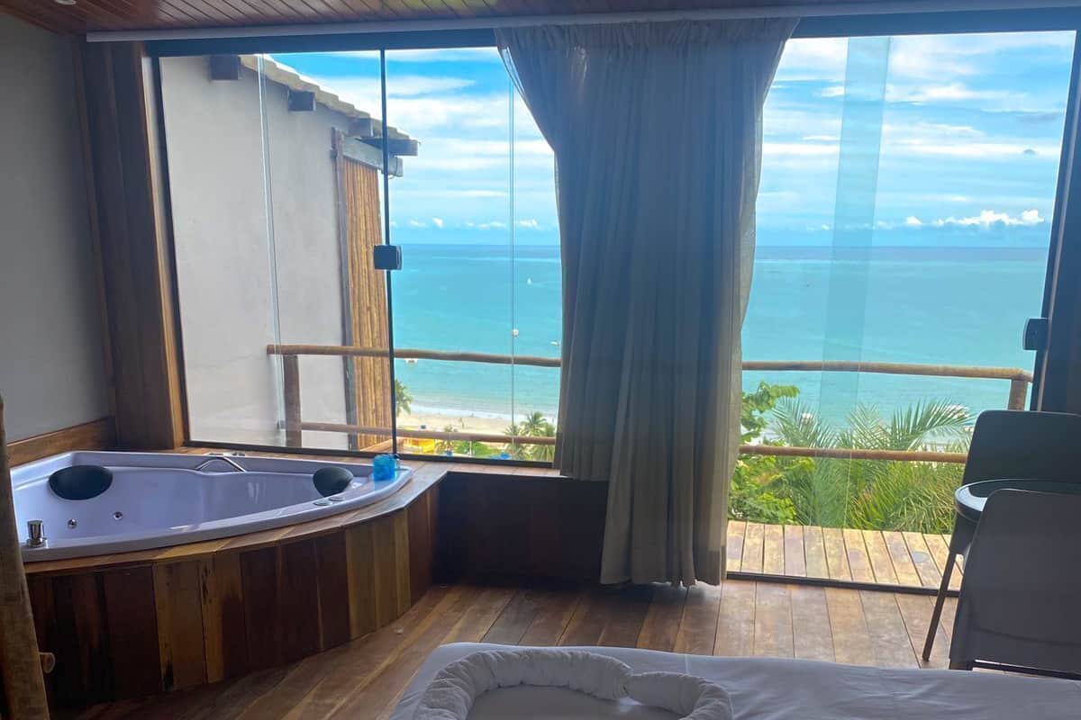 A room with a large bed, a bathtub, and a view of the ocean.