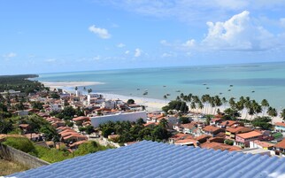 Un pueblo costero con playa, cielo azul despejado y mar tranquilo.