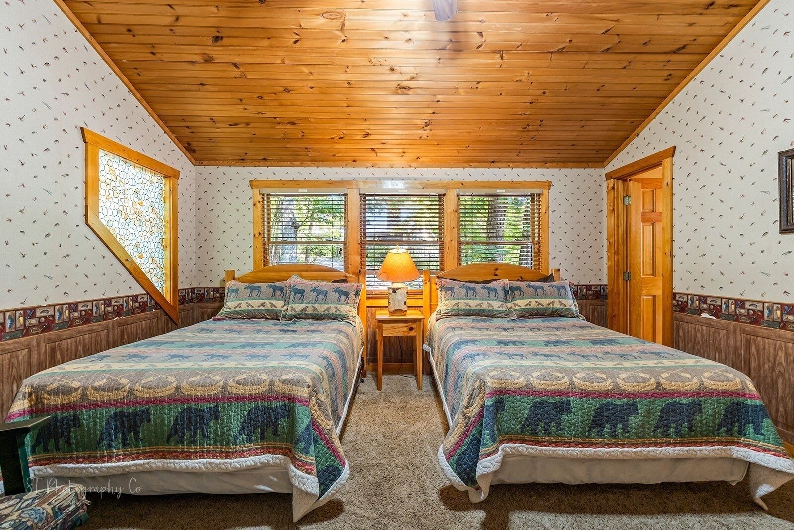A room with two beds, a wooden ceiling, and patterned walls.