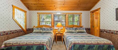 A room with two beds, a wooden ceiling, and patterned walls.