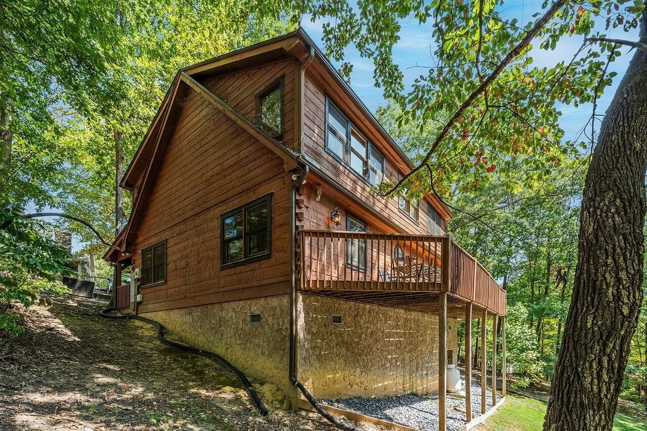 Une cabane en bois à deux étages, dotée d’un balcon et entourée d’arbres.