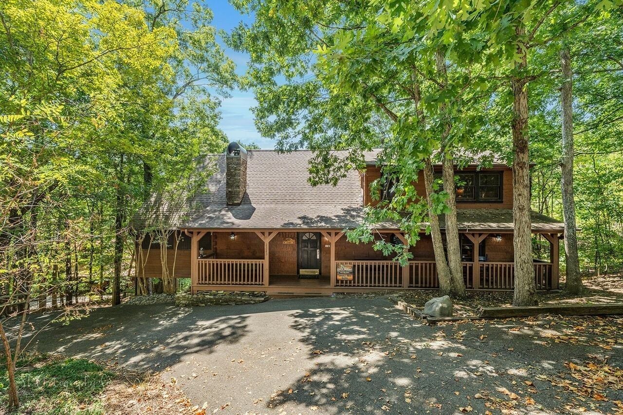 Une cabane dotée d’une véranda, entourée d’arbres.