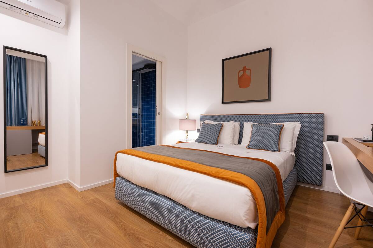 Habitación de hotel ordenada con una cama, un escritorio y una silla.