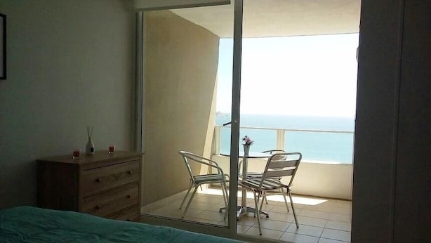 A bedroom with a sliding glass door leading to a balcony with a view of the sea. - Depto Costa Mansa (Coquimbo)