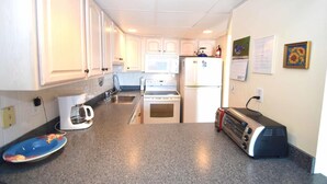 Eine kompakte Küche mit weißen Schränken, einer Mikrowelle, einem Kühlschrank, einem Toaster und einem Spülbecken.