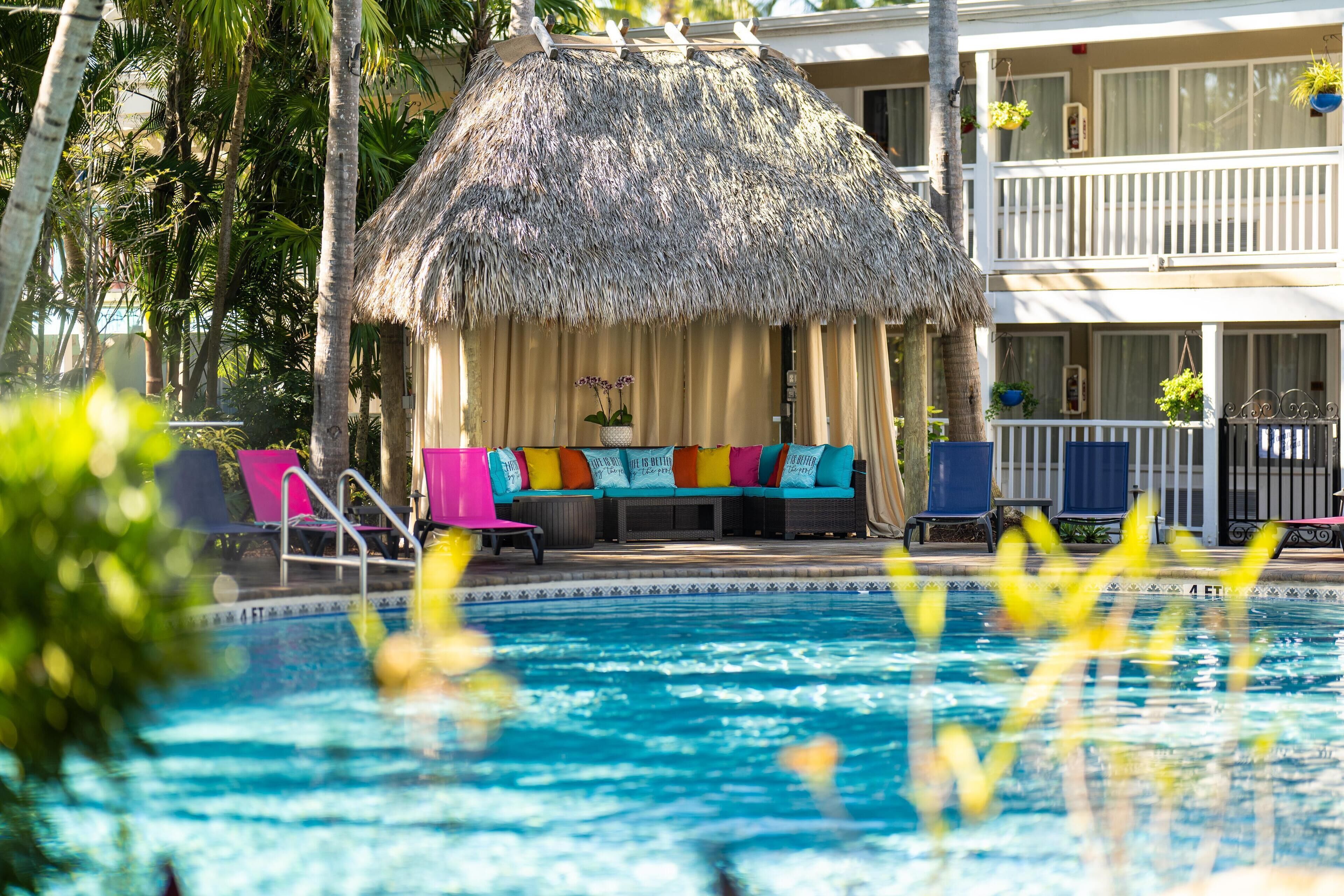 A pool area with a thatched-roof structure, lounge chairs, and a pool with a 4 ft depth marker.
