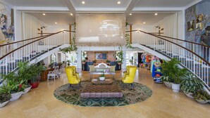 A spacious lobby with a central seating area, two staircases, and multiple potted plants. - Havana Cabana at Key West  (Key West)