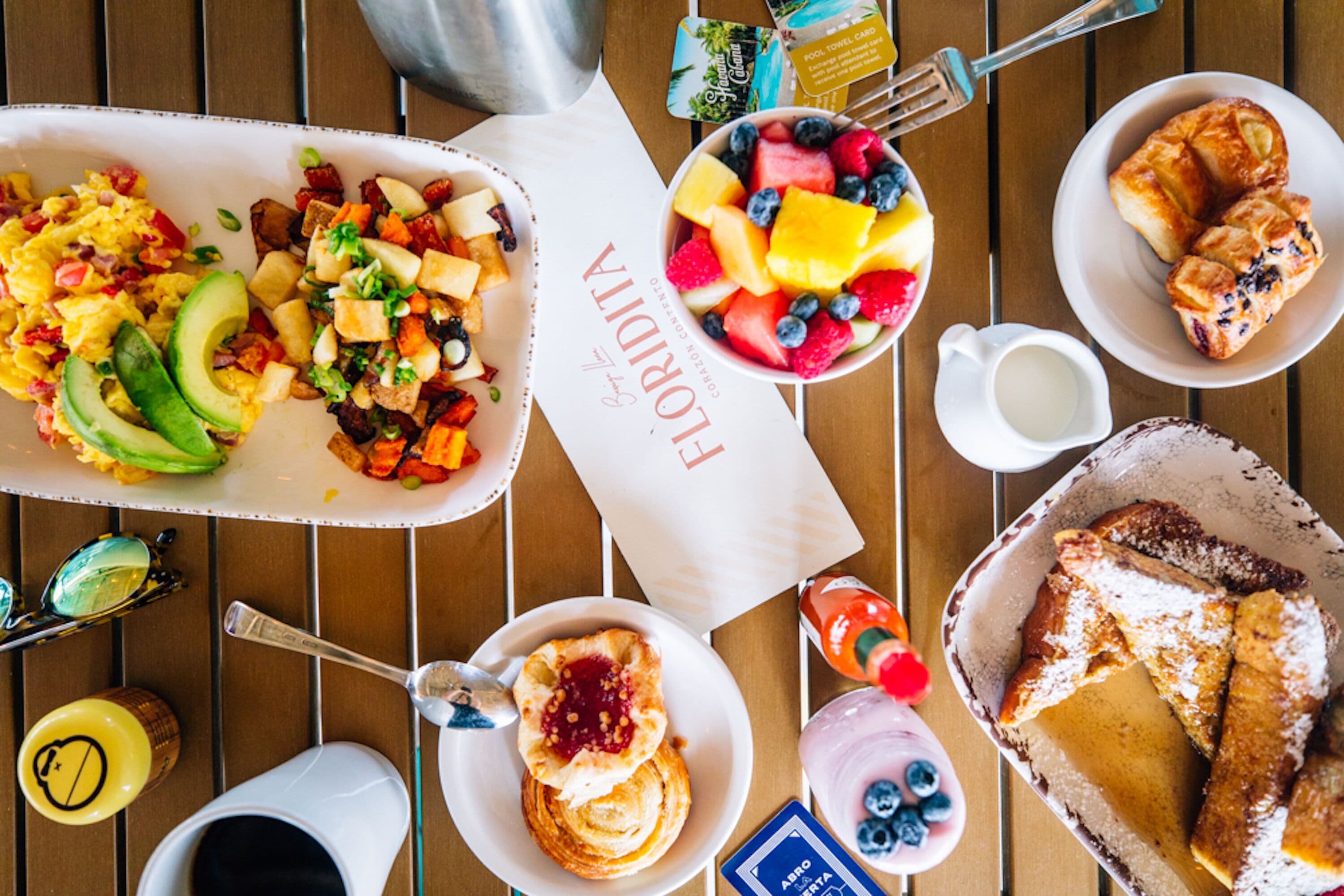 A breakfast spread with various dishes including eggs, avocado, toast, and fruit.
