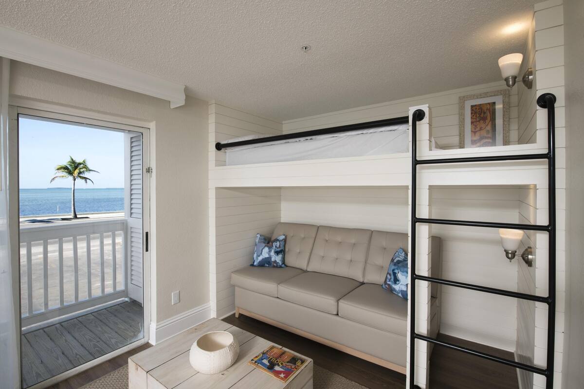 A room with a balcony, a sofa, a coffee table, and a ladder.