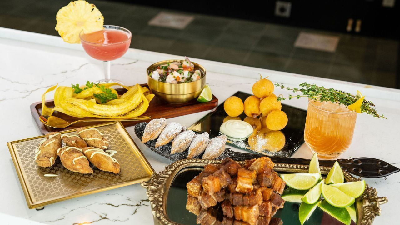 A table with various food items, a cocktail, and a bowl of shrimp cocktail.