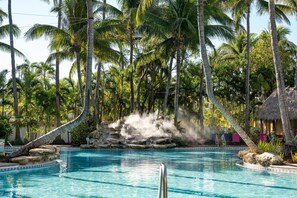 A swimming pool surrounded by palm trees and a natural rock formation. - Havana Cabana at Key West  (Key West)