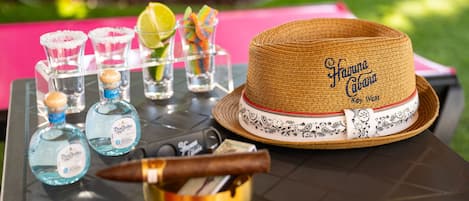 A table with a straw hat, shot glasses, bottles of Don Julio tequila, and a cigar.