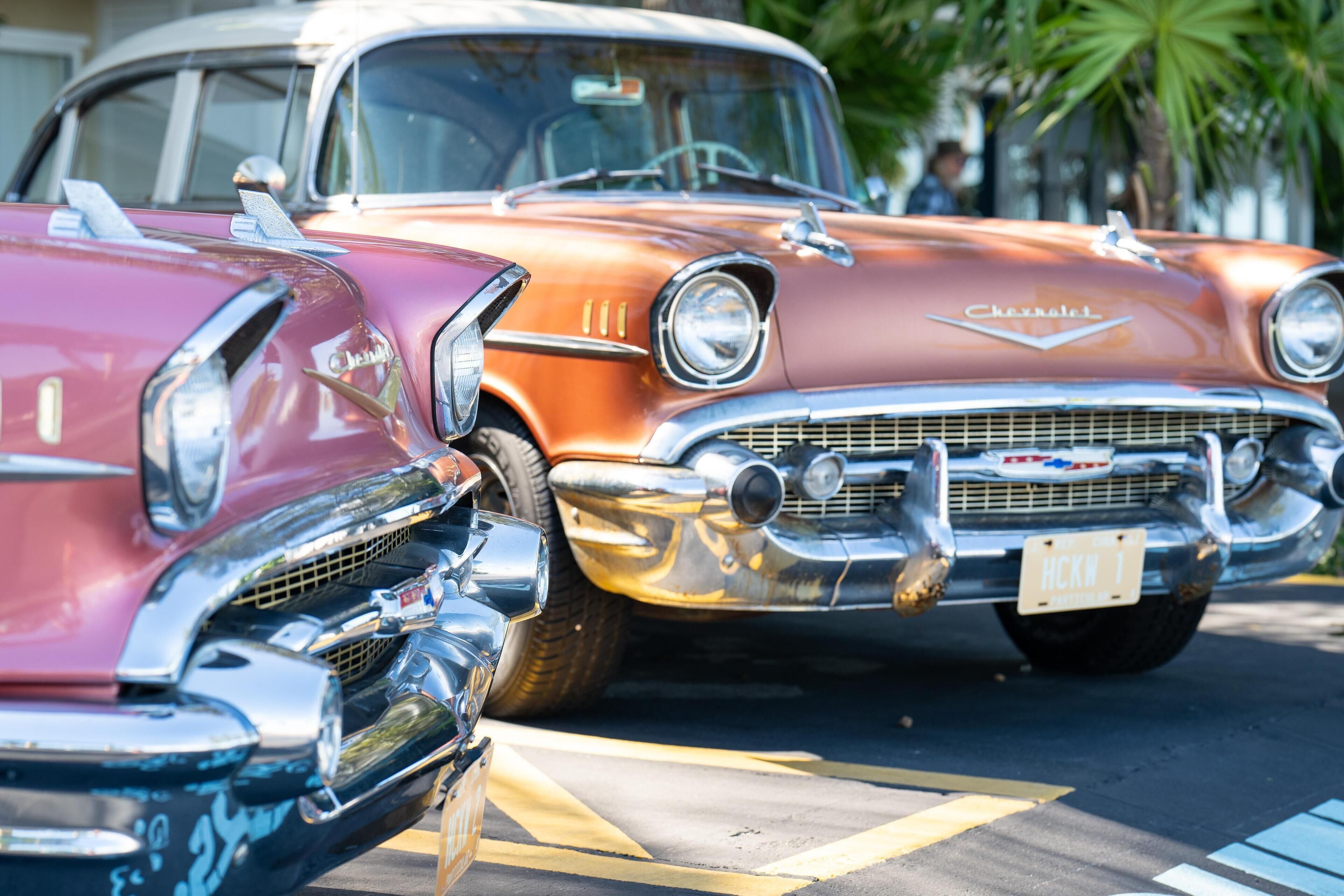A vintage car with a chrome grille and emblem, parked on a street with yellow lines.