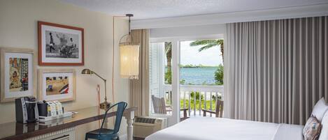 A hotel room with a bed, a desk with a chair, a coffee maker, and framed pictures on the wall.
