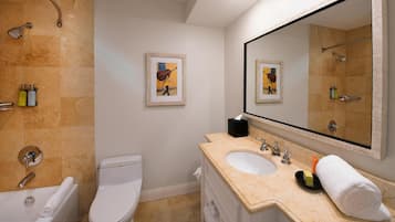 A bathroom with two sinks, a toilet, a bathtub, a shower, and two framed pictures on the wall.